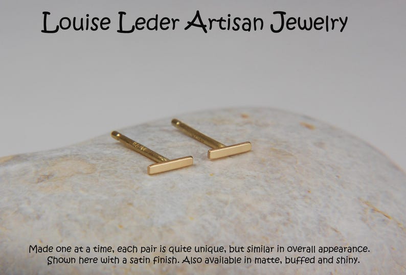 May include: A pair of gold-colored bar stud earrings. The earrings are displayed on a light-colored, textured surface. The text "Louise Leder Artisan Jewelry" is at the top. The text at the bottom says the earrings are unique.