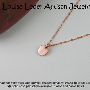 Puede incluir: Un delicado collar de oro rosa con un peque&ntilde;o colgante de forma org&aacute;nica. La cadena tiene un dise&ntilde;o fino y retorcido. El texto "Louise Leder Artisan Jewelry" est&aacute; en la parte superior. Joyas hechas a mano.