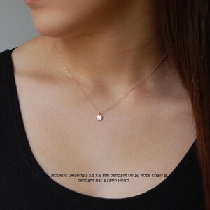 Puede incluir: Un delicado collar de oro rosa con un peque&ntilde;o colgante redondo. El colgante mide 5,5 x 6 mm y cuelga de una cadena de cuerda de 40,6 cm. El colgante tiene un acabado satinado. La modelo lleva un top negro.
