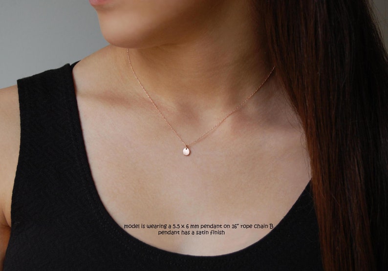 Puede incluir: Un delicado collar de oro rosa con un peque&ntilde;o colgante redondo. El colgante mide 5,5 x 6 mm y cuelga de una cadena de cuerda de 40,6 cm. El colgante tiene un acabado satinado. La modelo lleva un top negro.
