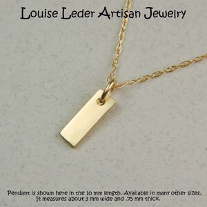 May include: A gold-coloured rectangular pendant necklace. The pendant is a small, polished rectangle suspended from a delicate chain. The necklace is from Louise Leder Artisan Jewelry. The pendant is 3 mm wide and .75 mm thick.