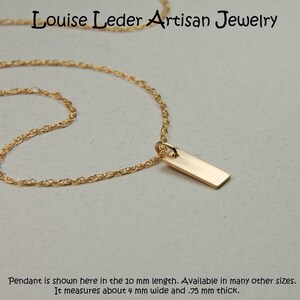 May include: A gold-colored necklace with a rectangular pendant. The pendant is approximately 4 mm wide and .75 mm thick. The necklace is from Louise Leder Artisan Jewelry.