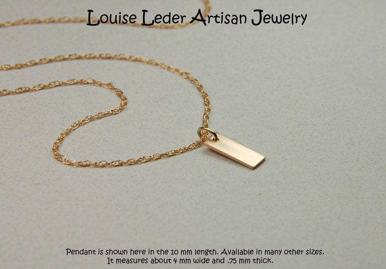 May include: A gold-colored necklace with a rectangular pendant. The pendant is approximately 4 mm wide and .75 mm thick. The necklace is from Louise Leder Artisan Jewelry.