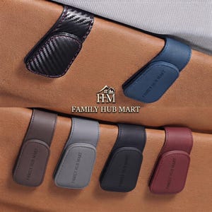 May include: Six magnetic car visor sunglass clips in various finishes including carbon fiber, blue, brown, gray, black, and maroon. Each clip features the embossed text FAMILY HUB MART and is attached to a tan leather-textured surface.