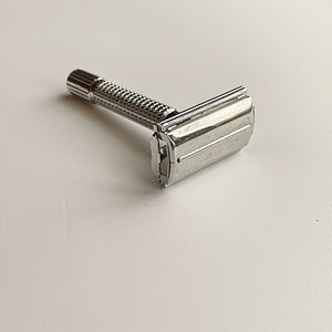 May include: A silver safety razor with a textured handle and a chrome blade.