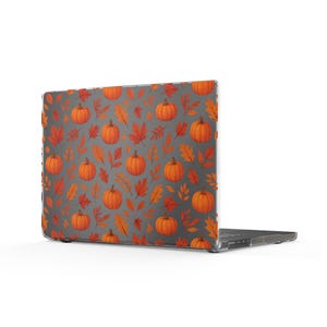May include: A laptop computer featuring a protective hard shell case with a dark gray background. The case displays a repeating pattern of orange pumpkins and various autumn leaves in shades of red, orange, and yellow across the surface.