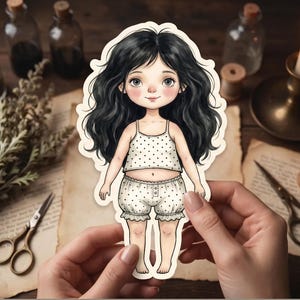 May include: A die-cut sticker of a cartoon character with long wavy black hair, large eyes, and rosy cheeks. The character wears a white two-piece outfit featuring a sleeveless top and ruffled shorts, both decorated with a small black polka dot pattern.