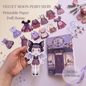 May include: A printable paper doll house set titled Velvet Moon Perfumery, featuring a bat-eared doll, various purple and pink outfits, and a shop front illustration. The set includes multiple paper cutouts of clothing and a digital download label.