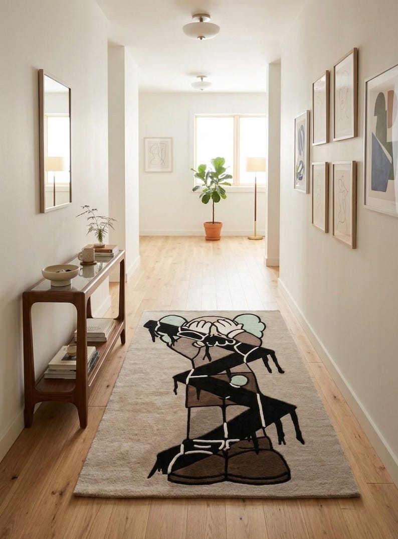 Abstract character hand tufted wool rug displayed in a bright hallway, modern designer area rug with black graphic artwork on a neutral cream background.