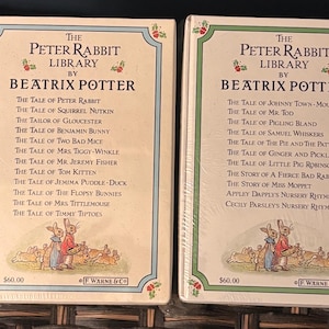May include: Two boxed sets of "The Peter Rabbit Library by Beatrix Potter" books. Each box features a cream-colored background with a green border and illustrations of Peter Rabbit and other characters. The titles of the stories are listed on the front.
