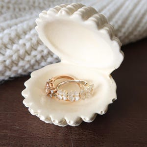 May include: A clear glass bottle with a textured surface. The bottle has a silver cap and a label with black text. The bottle appears to be filled with a liquid. The bottle is likely for essential oils or perfume.