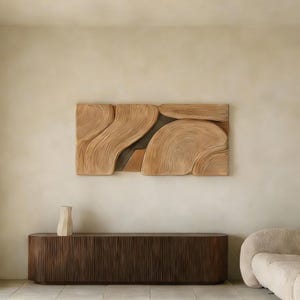 以下が含まれることがあります： 自然な木材仕上げの大きな抽象的な木製ウォールアートで、流れるような有機的な形が特徴です。 下には、垂直の溝とクリーム色の花瓶が付いた濃い茶色の木製キャビネットがあります。 部屋はニュートラルな色調です。