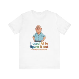 Peut inclure: T-shirt blanc avec une illustration de dessin animé d'un homme en chemise bleue. Le texte "I used AI to figure it out" est imprimé en bleu, vert et orange, avec "Average Intelligence" en dessous.
