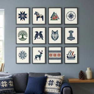May include: A collection of framed art prints with Scandinavian-inspired designs. The prints feature geometric patterns, animals, and Viking symbols in navy, red, and cream colors. The artwork is displayed above a gray sofa with matching throw pillows and a blue blanket.