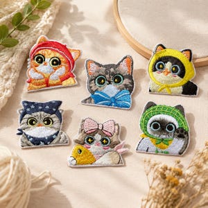Puede incluir: Seis parches bordados de gatos con varios diseños: un gato naranja con capucha roja, un gato atigrado gris con lazo azul, un gato blanco y negro con capucha amarilla, un gato gris con pañuelo azul, un gato calicó con lazo rosa y un siamés con sombrero verde.