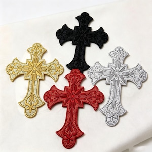 Op de afbeelding: Vier geborduurde kruis-patches in zwart, goud, rood en zilver. Elke patch heeft een ingewikkeld, symmetrisch, bloemachtig ontwerp met sierlijke, gebogen randen en een centraal stervormig motief, uitgevoerd in dicht, getextureerd garen.