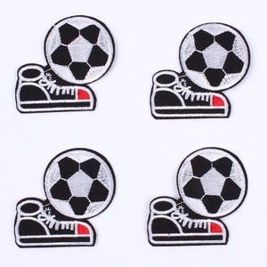 Puede incluir: Cuatro parches bordados con un balón de fútbol y una zapatilla deportiva. Los balones son negros y blancos, y las zapatillas son negras con cordones blancos y un acento rojo en la suela. Sobre un fondo blanco.