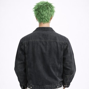 May include: A black denim jacket with a classic collar and button closures. The jacket has a simple, clean design, with a focus on the dark wash of the denim. The back view shows the jacket's tailored fit and the details of the stitching.