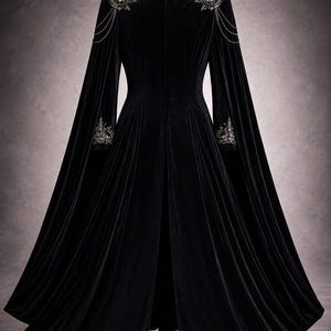 May include: A long, black velvet cloak with a high collar and flowing sleeves. The cloak features intricate silver embroidery and chain detailing on the shoulders and cuffs, creating an elegant, gothic aesthetic.