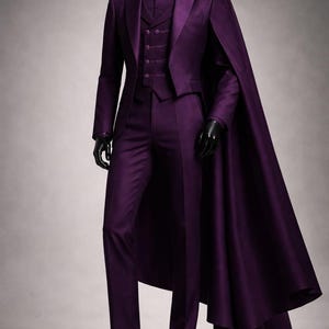 May include: A formal purple suit with a matching cape, vest, and trousers. The suit is displayed on a mannequin with a black head and hands. The ensemble includes a collared shirt and black dress shoes.
