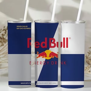 Puede incluir: Tres vasos de acero inoxidable con pajitas blancas. Los vasos presentan el logotipo de Red Bull en rojo y azul, con el texto "SERVED CHILLED MAY GIVE YOU WINGS" y "VITALIZES BODY AND MIND."