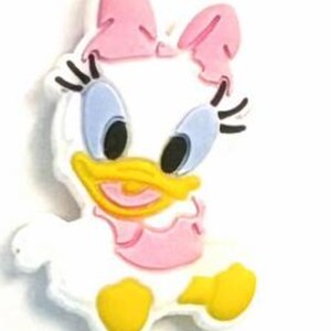May include: A white, pink, yellow, and black Daisy Duck charm. The charm features a pink bow, blue eyes, and a yellow beak. The charm is a cartoon character.