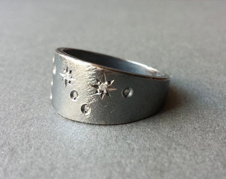 Puede incluir: Un anillo de plata con una superficie texturizada y peque&ntilde;os diamantes engastados en forma de estrellas.