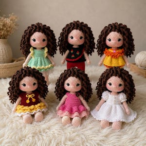 May include: Six handmade crochet dolls with curly brown yarn hair and embroidered facial features. Each doll wears a unique outfit: a light green dress, a black top with red pants, a yellow dress, a red dress, a pink dress, and a white dress.