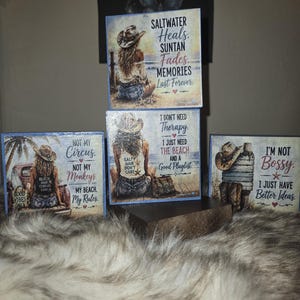 May include: Three square wooden signs featuring illustrations of a person in a cowboy hat at the beach. The signs display text including Saltwater Heals, I Don't Need Therapy, I Just Need The Beach, Not My Circus, Not My Monkeys, and I'm Not Bossy.
