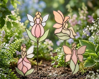 May include: Four stained glass garden stakes featuring fairy figures in pastel pink, cream, and green tones. Each fairy is depicted with delicate wings and floral-inspired bodies, mounted on thin metal rods for placement in soil.