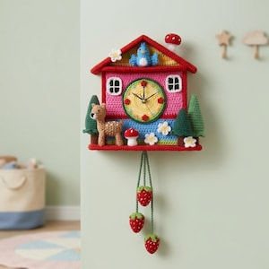 Puede incluir: Un reloj de ganchillo hecho a mano con forma de casa. El reloj presenta una fachada rosa, un tejado rojo y una esfera amarilla. Los elementos decorativos incluyen un ciervo, árboles, flores y colgantes de fresas. El reloj está montado en una pared verde claro.