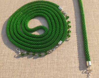 May include: A long, coiled green beaded necklace and a matching straight green beaded bracelet. Both pieces feature a dense, tubular weave of small green beads, silver-toned metal end caps, and silver-toned lobster claw clasps with chain links.