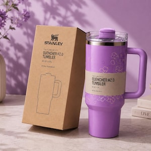 May include: A lilac Stanley Quencher H2.0 tumbler with a handle and a matching box. The tumbler has a floral design and holds 1.18L of liquid. The box features the Stanley logo and product details.
