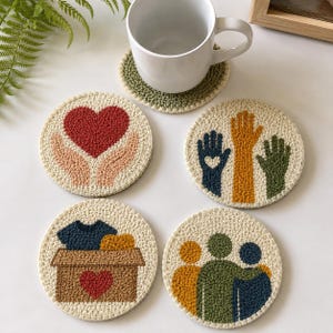 May include: Five circular coasters with embroidered designs in various colours. One shows a red heart in hands, another has hands with a heart, and others depict a box of clothes, and figures embracing. A white mug rests on a green coaster.
