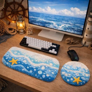 May include: A desktop setup featuring a keyboard, mouse, and a beach-themed rug and coaster. The rug and coaster have a blue, white, and yellow design with a starfish. A computer monitor displays a seascape.