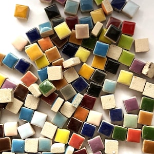 May include: A set of three ceramic mugs with a speckled, matte finish. The mugs are in shades of cream, light gray, and dark gray. Each mug has a simple, minimalist design, perfect for coffee or tea.