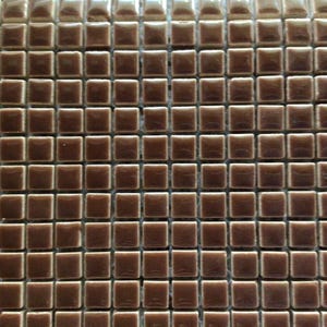 May include: Close-up of a mosaic tile sheet. The tiles are small, square, and a warm brown color. The tiles have a glossy finish, reflecting light. The pattern is a grid of evenly spaced tiles, suitable for various design applications.