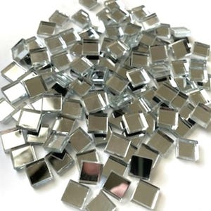 May include: A pile of small, square, mirrored glass tiles. The tiles are silver and reflect light, creating a shimmering effect. These mosaic tiles are ideal for craft projects and home decor.