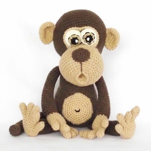 Könnte beinhalten: Eine handgefertigte Häkelpuppe in Braun- und Beigetönen. Der Affe hat große, ausdrucksstarke Augen, eine beige Schnauze und einen runden Bauch. Seine Arme und Beine sind ausgestreckt, und er scheint zu sitzen. Die Puppe ist aus weichem Garn gefertigt.