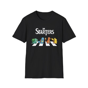 May include: Black t-shirt with the words "The Starters" above a cartoon illustration of four characters crossing a white zebra crossing. The characters are a green dinosaur, a blue turtle, an orange lizard, and a yellow mouse.