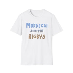 May include: White t-shirt with the text "MORDECAI AND THE RIGBYS" in blue and brown lettering. The shirt has short sleeves and a crew neck. The design is centered on the front of the shirt.
