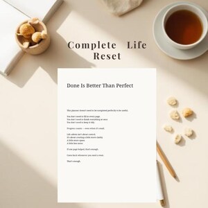 May include: A flat lay composition with a planner displaying "Done Is Better Than Perfect" and "Complete Life Reset." The scene includes a cup of tea, snacks, and stationery, set against a neutral backdrop.