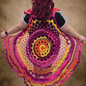 May include: A circular crochet vest featuring a vibrant mandala pattern in shades of magenta, bright pink, orange, and yellow. The garment is constructed with an openwork stitch design, creating a scalloped edge and a layered, radiating appearance.