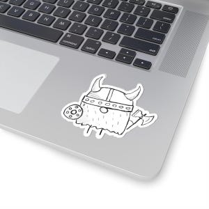 May include: A black and white sticker featuring a cartoon Viking character. The Viking is drawn with a horned helmet, shield, and axe. The sticker is placed on a laptop.