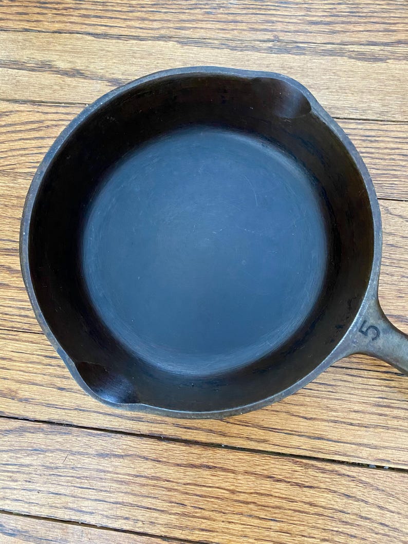May include: A black cast iron skillet with a 5 stamped on the handle.