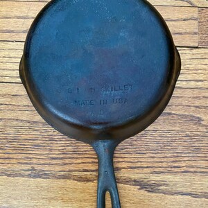 May include: A black cast iron skillet with a handle. The bottom of the skillet is marked with the text "8" "1" "SKILLET" "MADE IN USA".