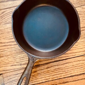 May include: A black cast iron skillet with a long handle. The skillet is empty and has a smooth, dark surface.