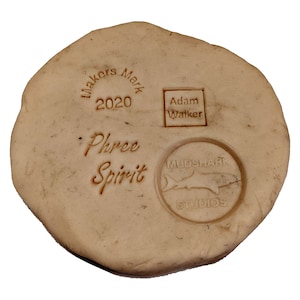 K&ouml;nnte beinhalten: Eine beige Tonplatte mit mehreren Stempeln. Die Stempel beinhalten "Makers Mark 2020", "Adam Walker", "Phree Spirit" und "Mudshark Studios" mit einer Haifischsilhouette.