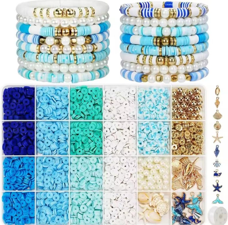 May include: A jewelry making kit featuring two stacks of blue, white, and gold bracelets, a rectangular storage container with twenty-four compartments filled with assorted flat round clay beads, white pearls, and gold metallic beads, plus various charms.