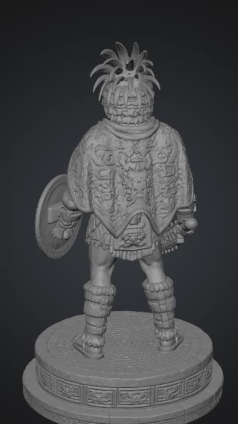 May include: A gray 3D rendered figurine of a warrior standing on a circular stone base. The figure wears a feathered headdress, a detailed cape with intricate carvings, and leg wraps. A round shield is held in the left hand and a weapon in the right.